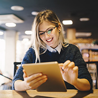 Photo of a woman looking at content on a tablet.